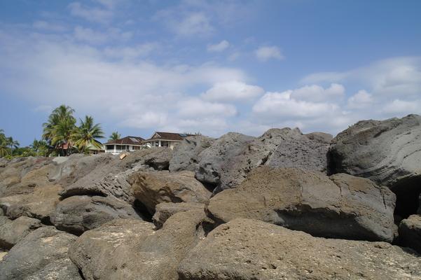 Large volcanic rocks stacked up along the edge of the beach and the civilization beyond... bringing a measure of safety when large waves break and threaten to wash over the road...